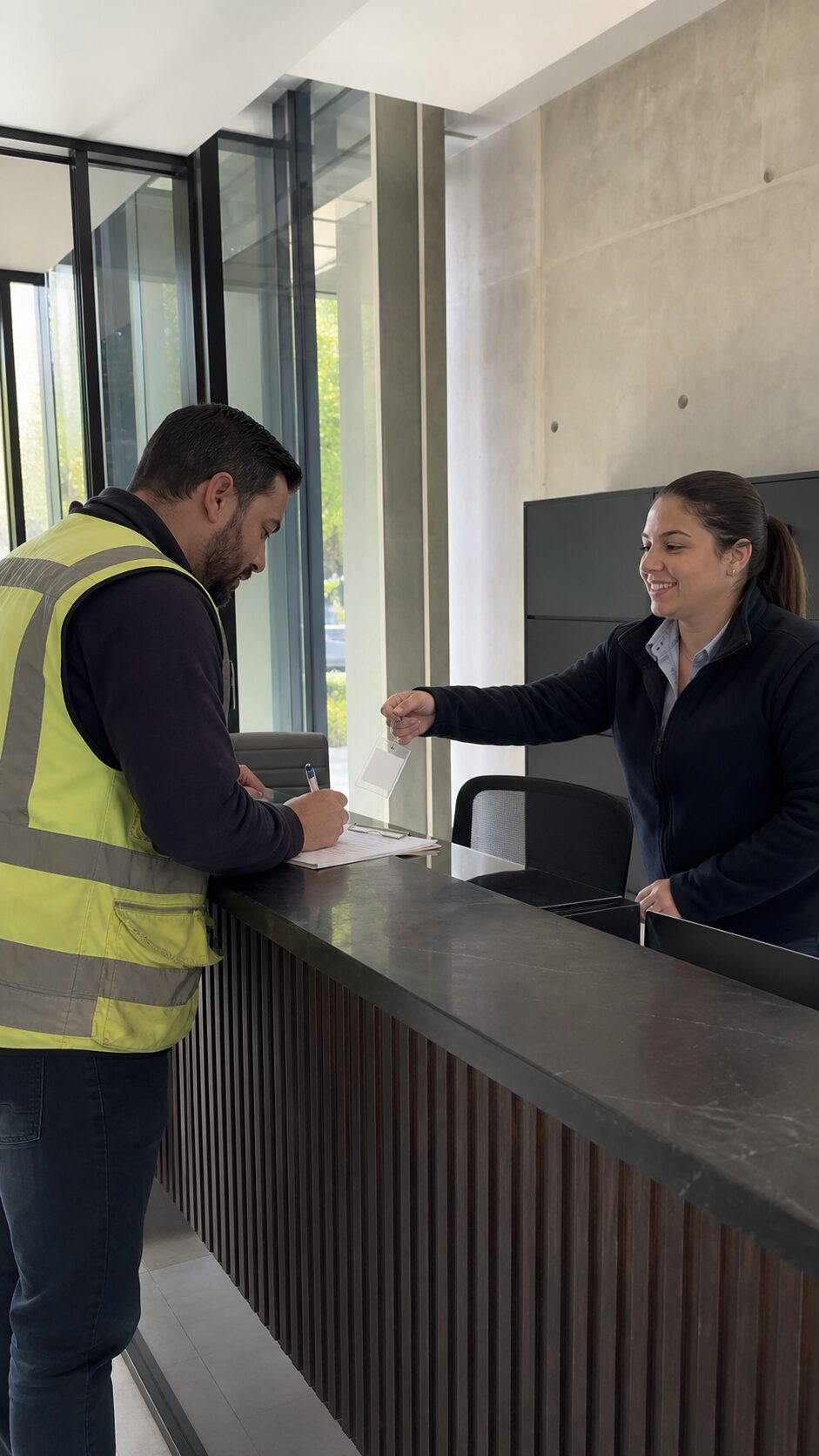 Recepción, visita con chaleco de proveedor firmando